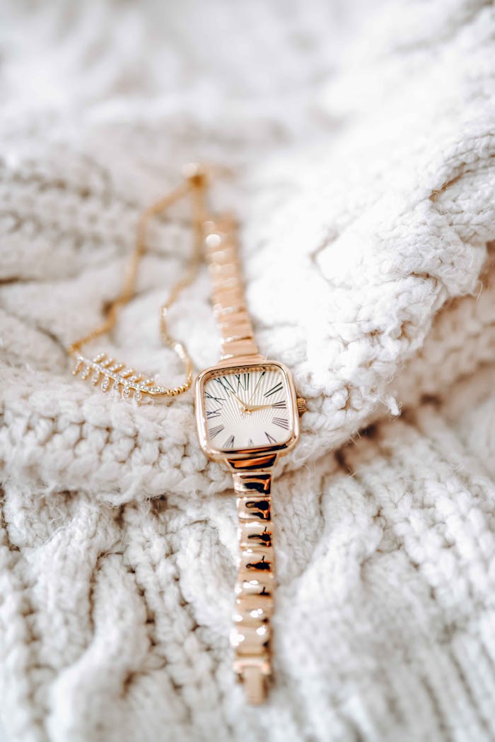 Close-up of a stylish gold watch resting on a soft knit sweater, perfect for elegant winter fashion.